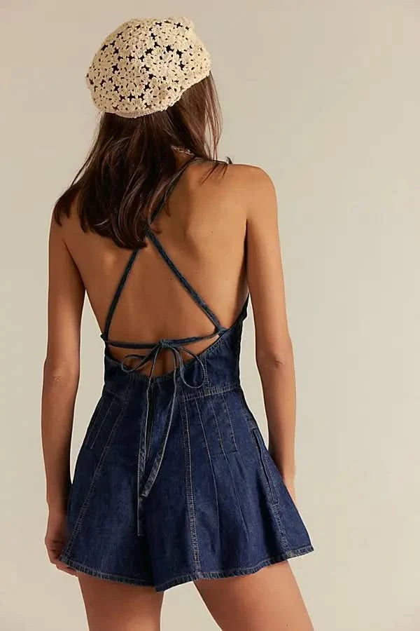 Back view of dark blue denim romper showing lace-up tie closure and pleated shorts