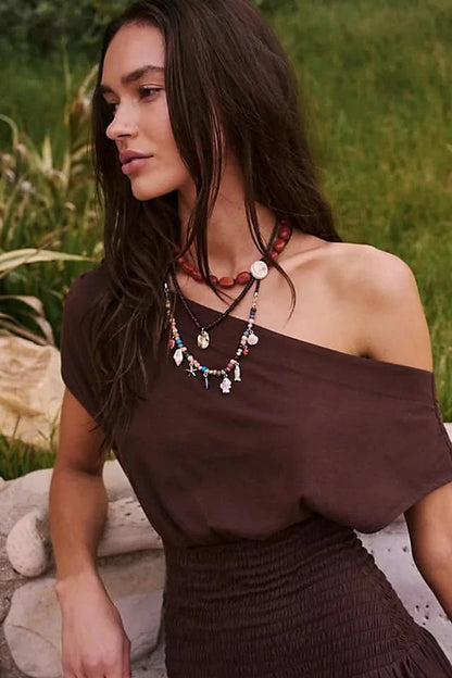 Close-up of brown off-shoulder mini dress with layered necklaces