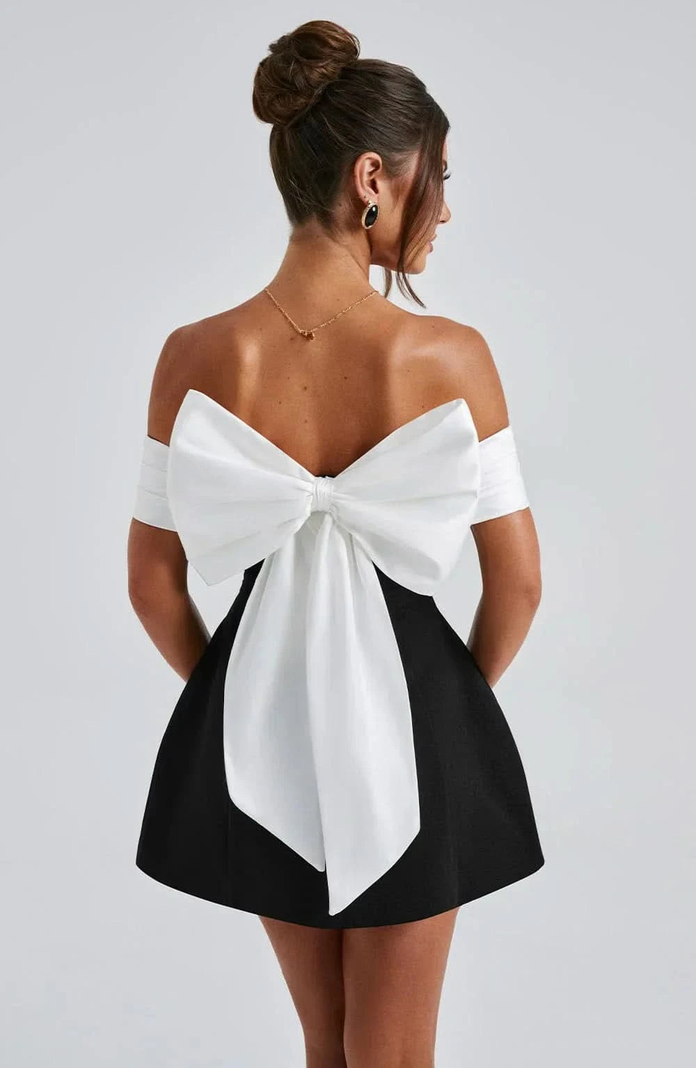 Back view of black mini dress with large white bow accent
