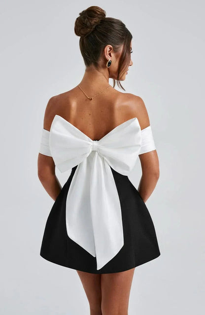 Back view of black mini dress with large white bow accent
