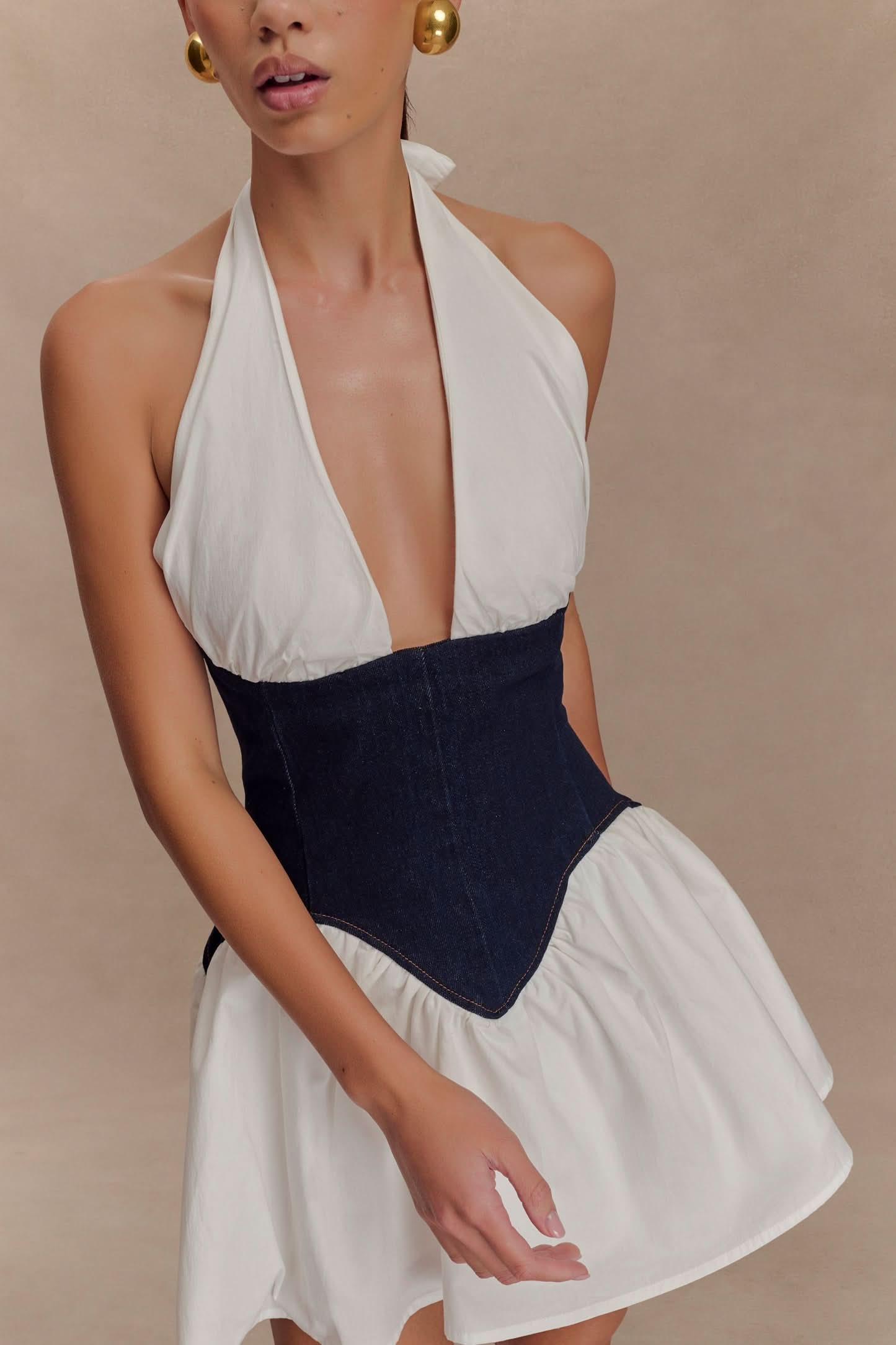 Close-up of halter mini dress neckline with white fabric and navy denim corset detail