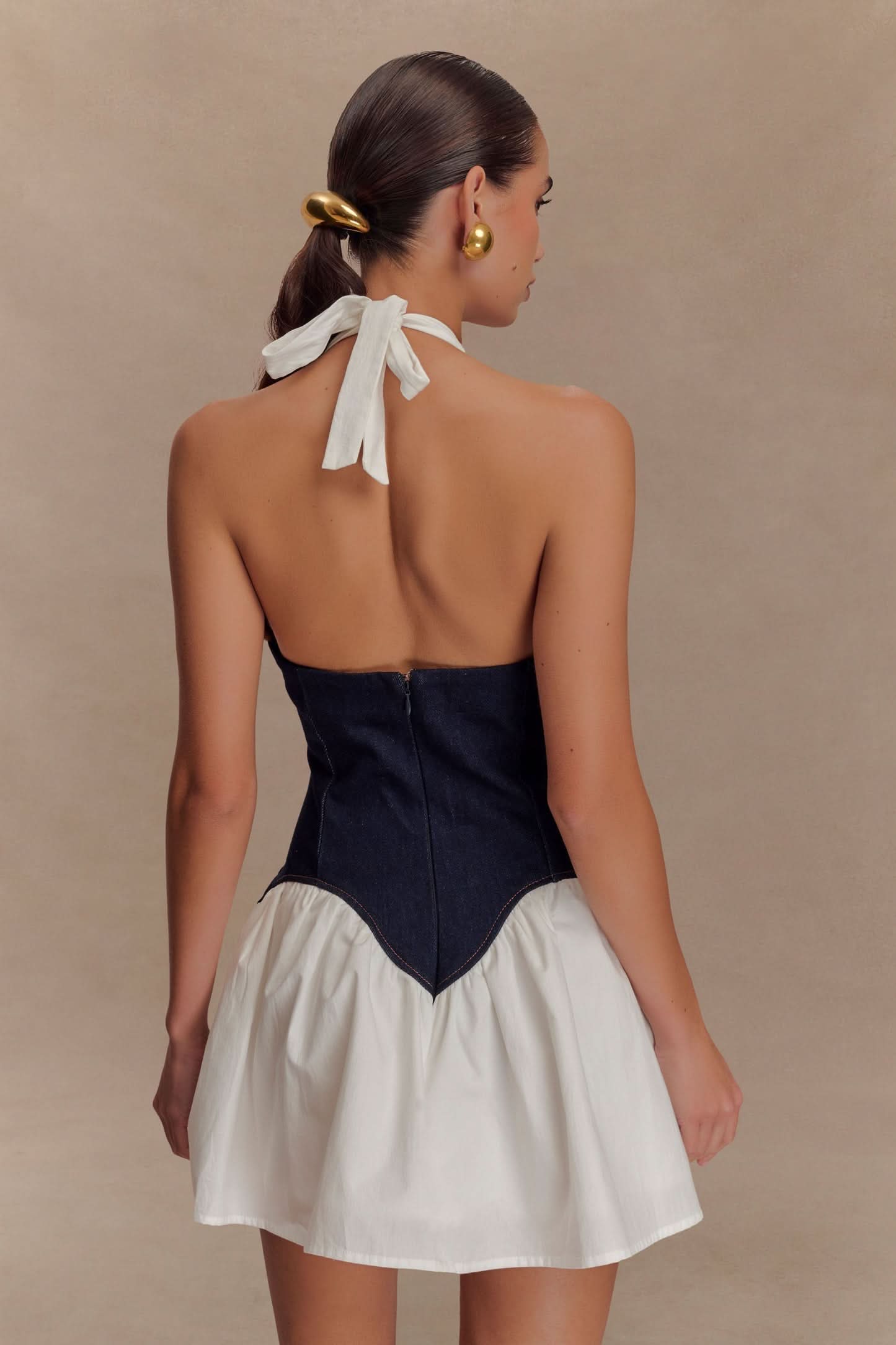 Back detail of halter mini dress showing white tie and navy denim corset seaming