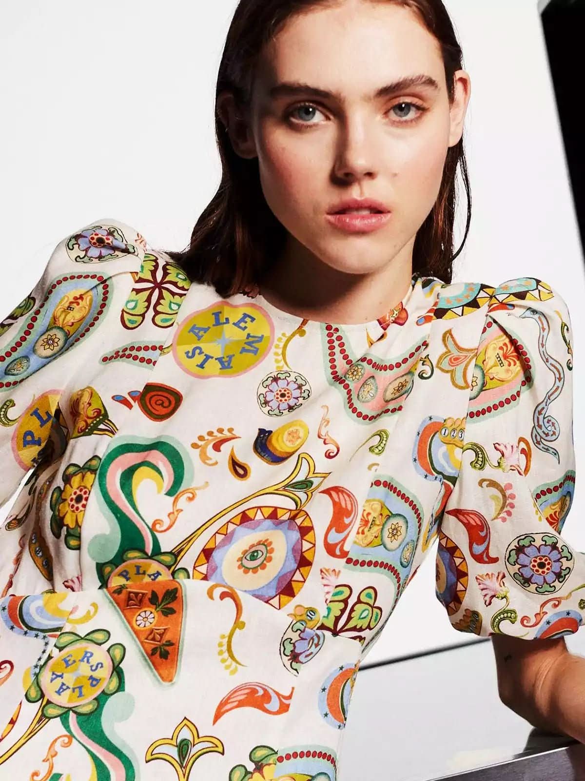 Close-up of vibrant multicolor paisley print with yellow, green, red and blue motifs on cream