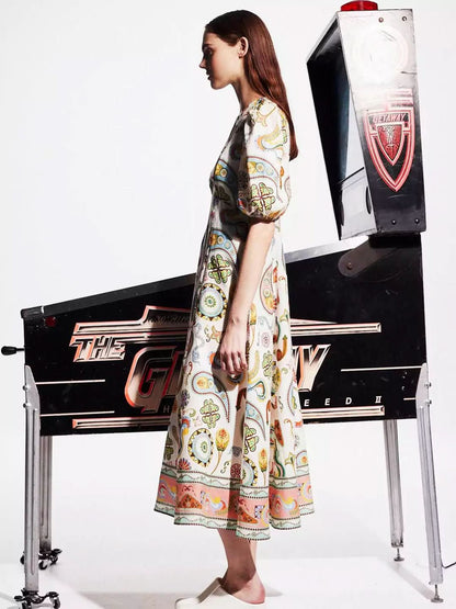 Side profile of cream midi dress with colorful print and coral-toned hem band detail