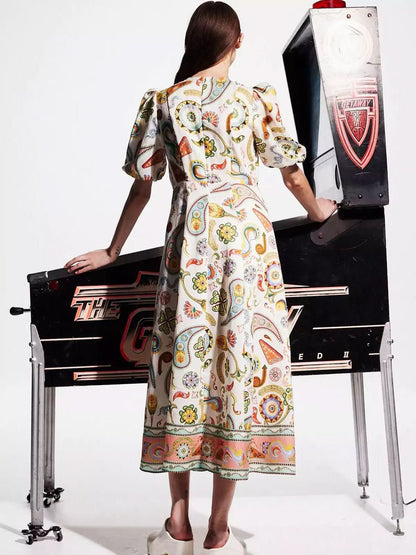 Back view of cream midi dress showing puffed sleeves and full skirt with coral border hem