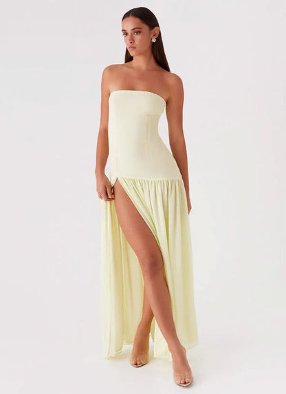 Pale yellow strapless maxi dress with thigh slit and flowing hem, angled view