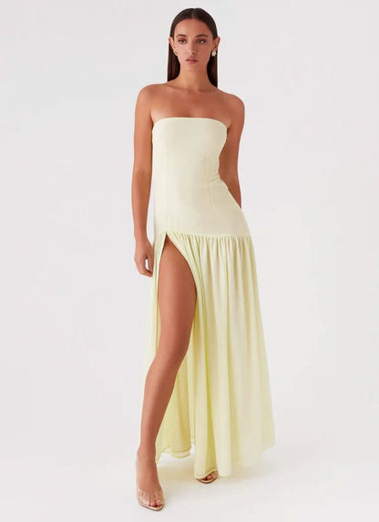 Pale yellow strapless maxi dress with thigh slit and flowing hem, angled view