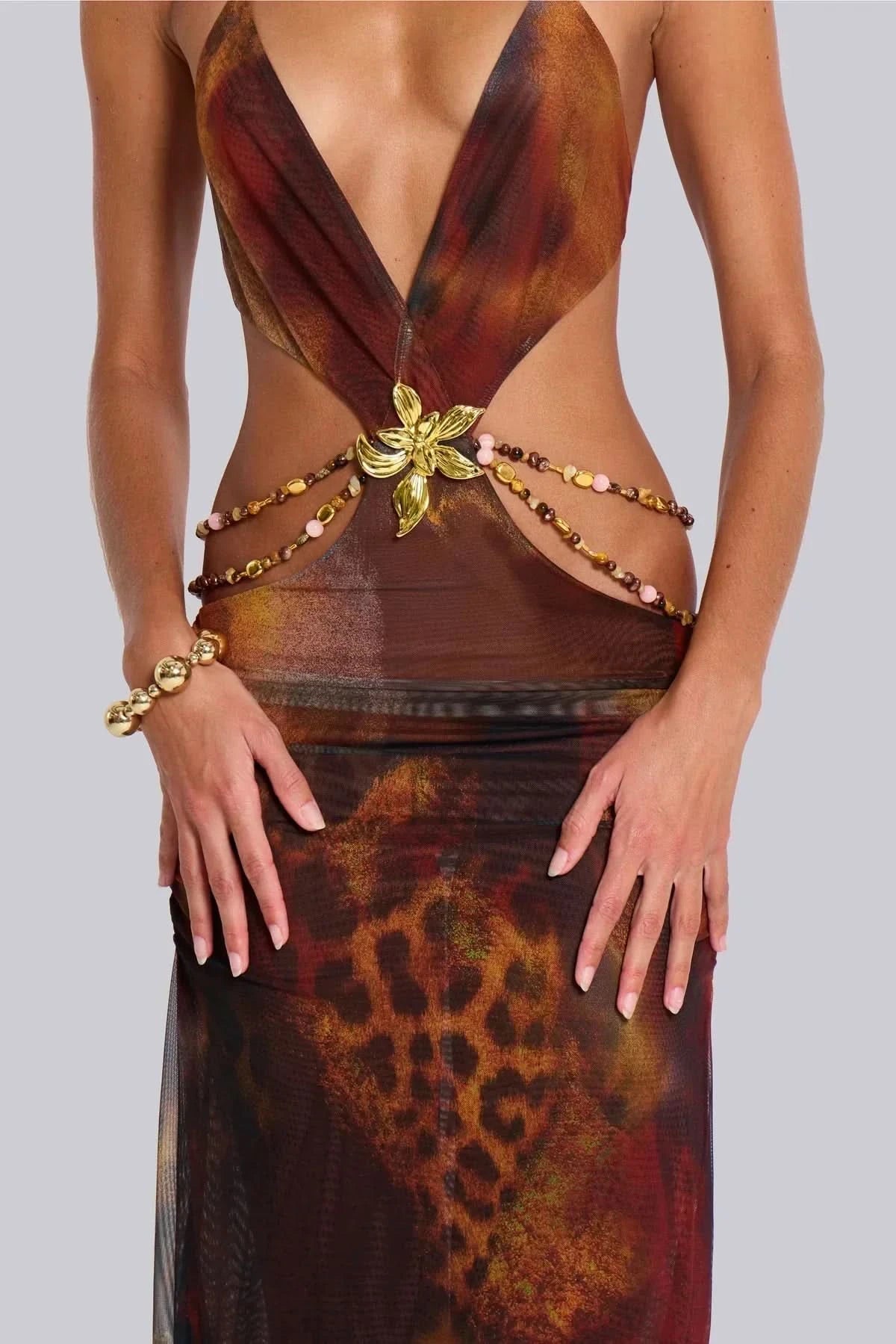 Close-up of gold butterfly and beaded chain waist embellishment on animal print maxi