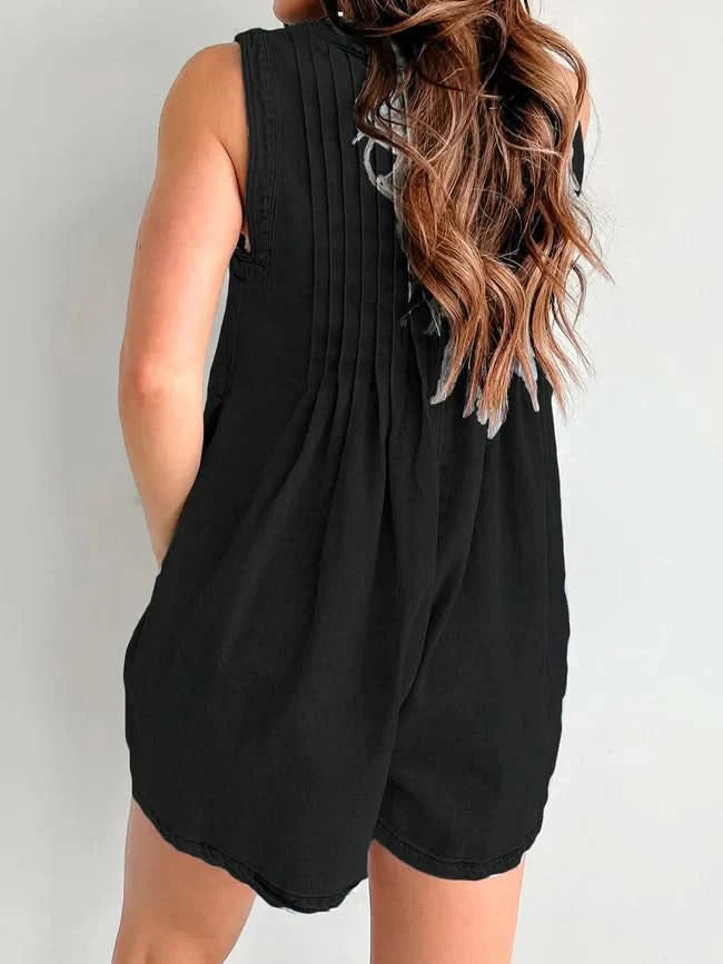 Black denim romper back view with pleated design and rounded hem