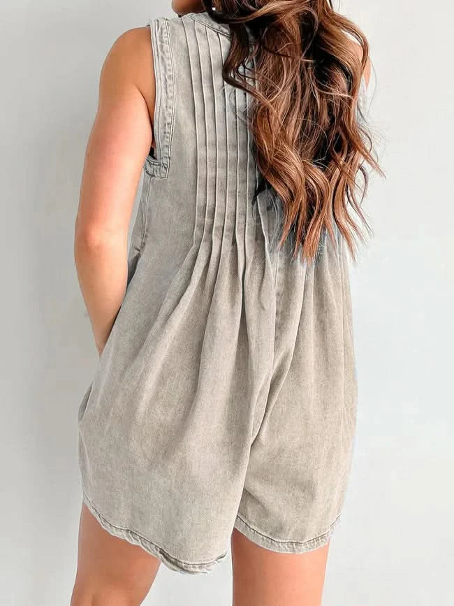 Light gray denim romper back view with pleated details and curved silhouette
