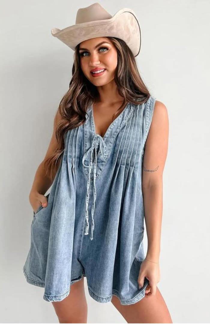 Light blue denim romper with lace-up front and pleated details