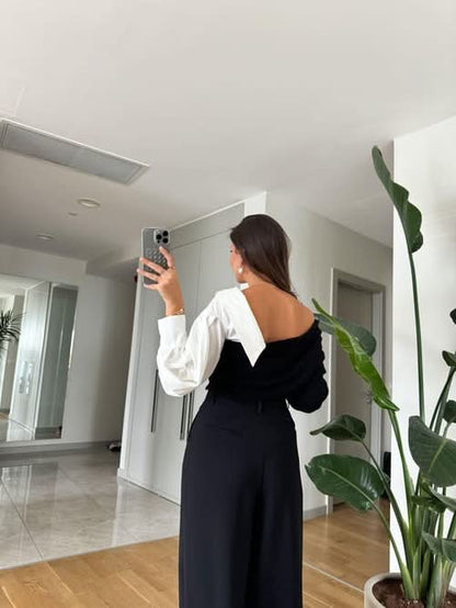 Back view of black and white two-tone sweater with draped white sleeves
