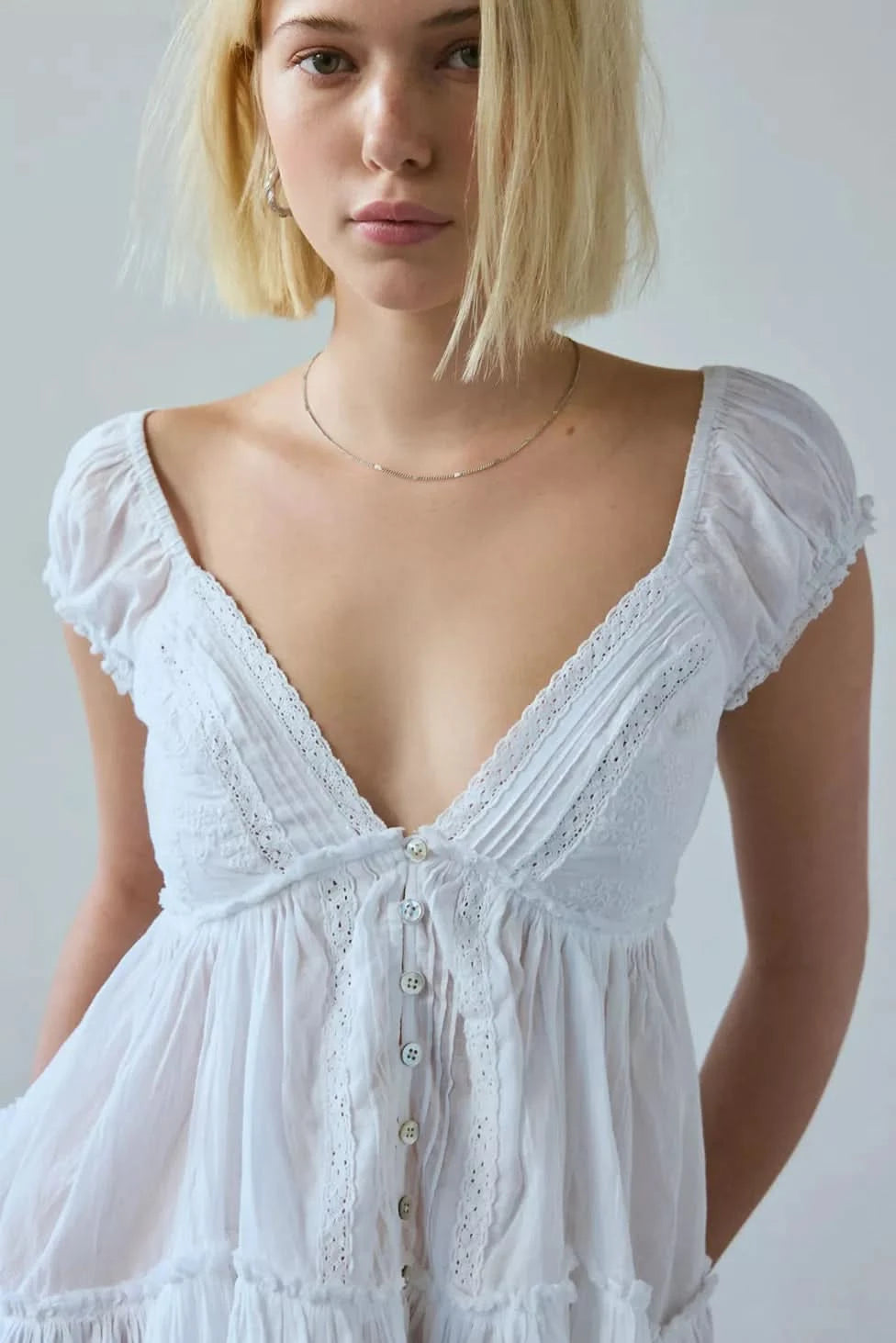 Close-up front view of white blouse with V-neckline, lace trim, and button-front closure for women