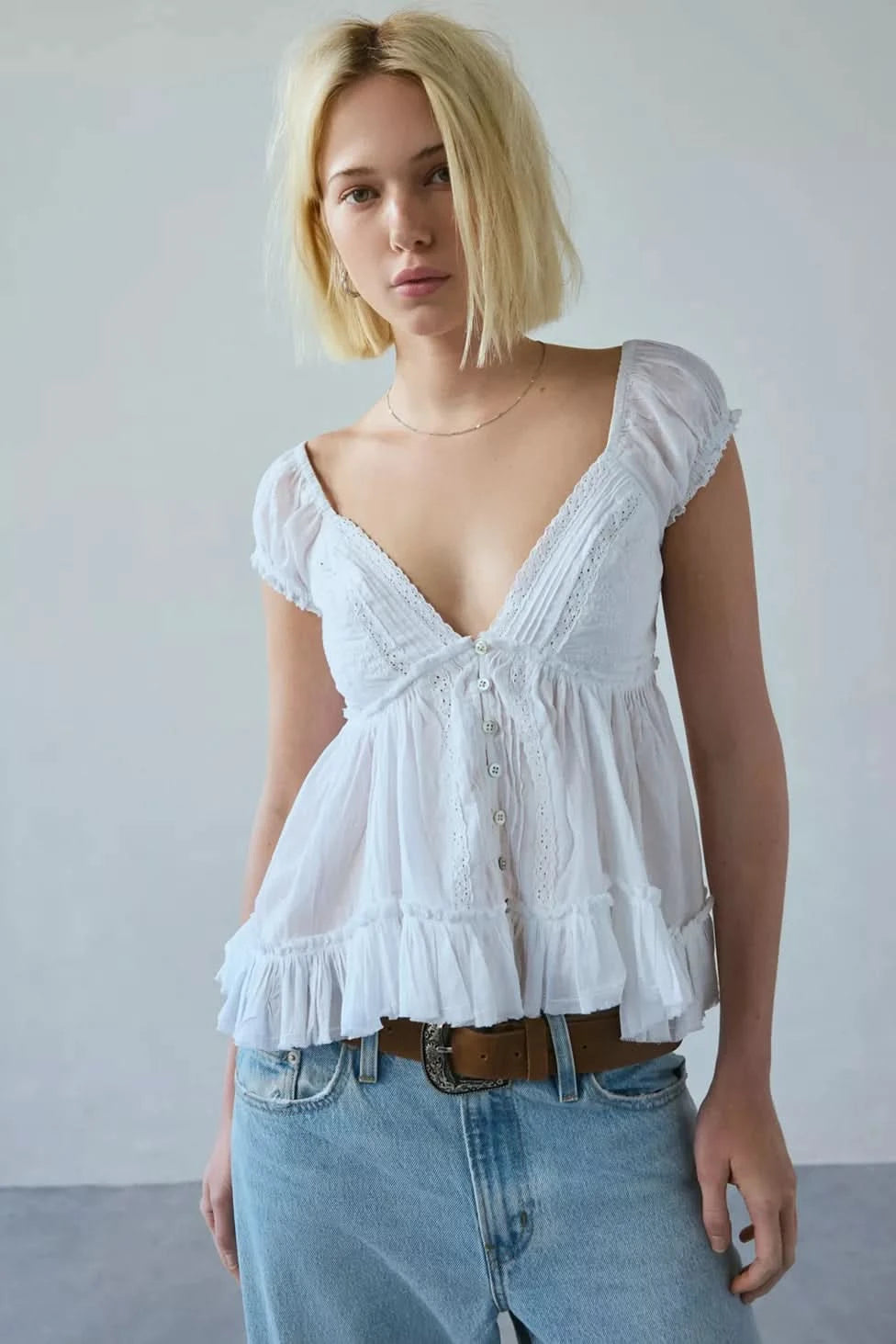 White peplum blouse with short puffed sleeves and tiered ruffle hem styled with denim for women