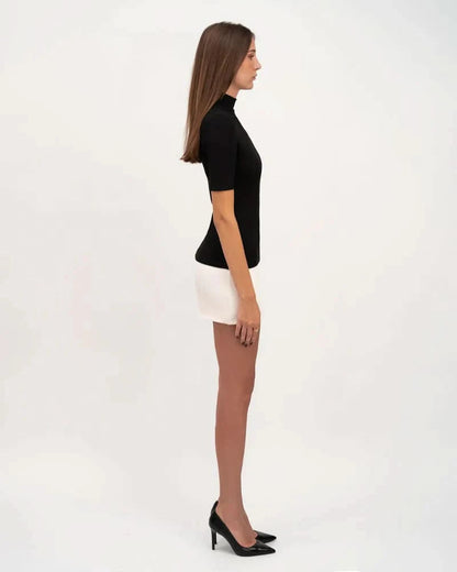 Side profile of black and white color-block mini dress showing fitted silhouette and A-line skirt