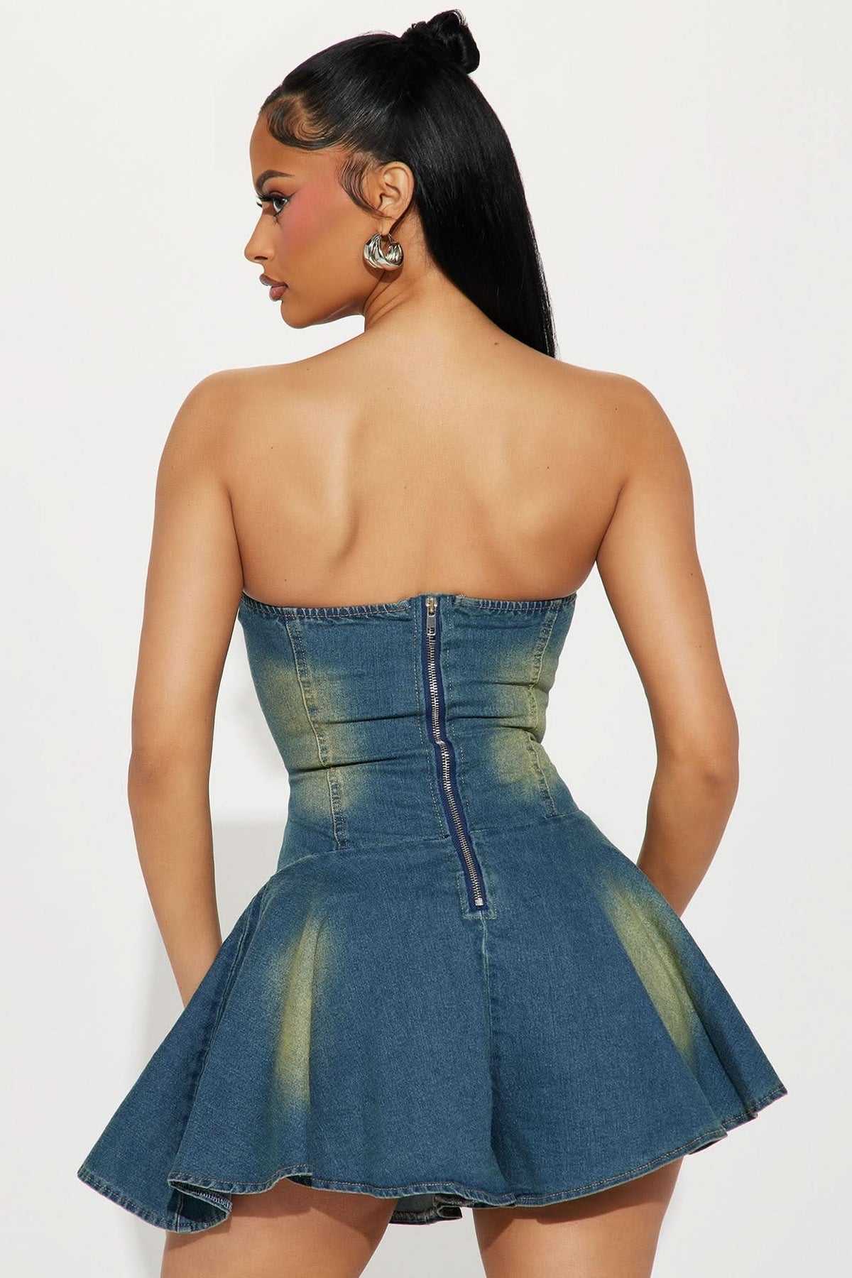 Back view of denim romper showing open back with center zip closure and flared mini skirt