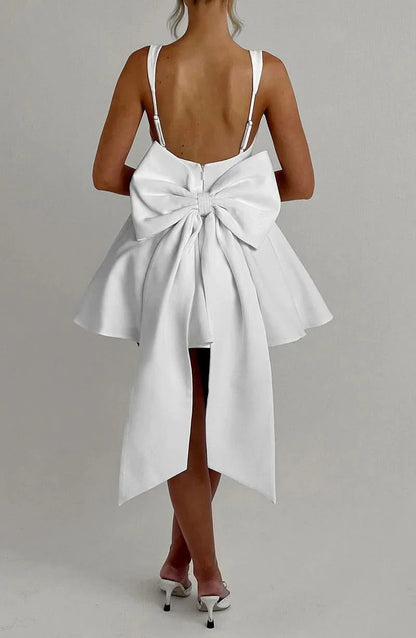 White mini dress back view showcasing prominent bow and asymmetrical skirt
