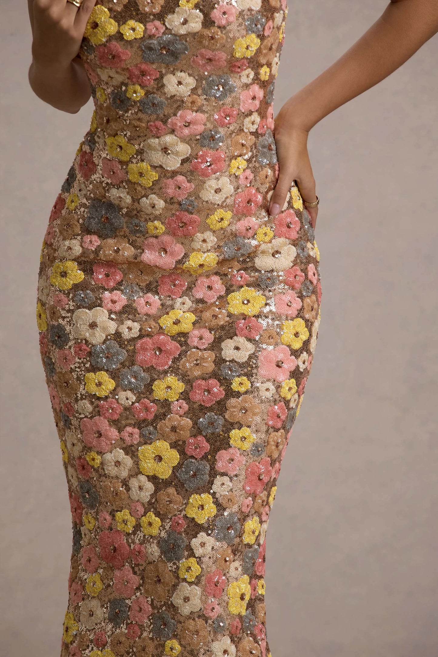 Close-up of 3D floral sequin fabric texture on women's maxi dress showing pink, yellow, and cream flowers
