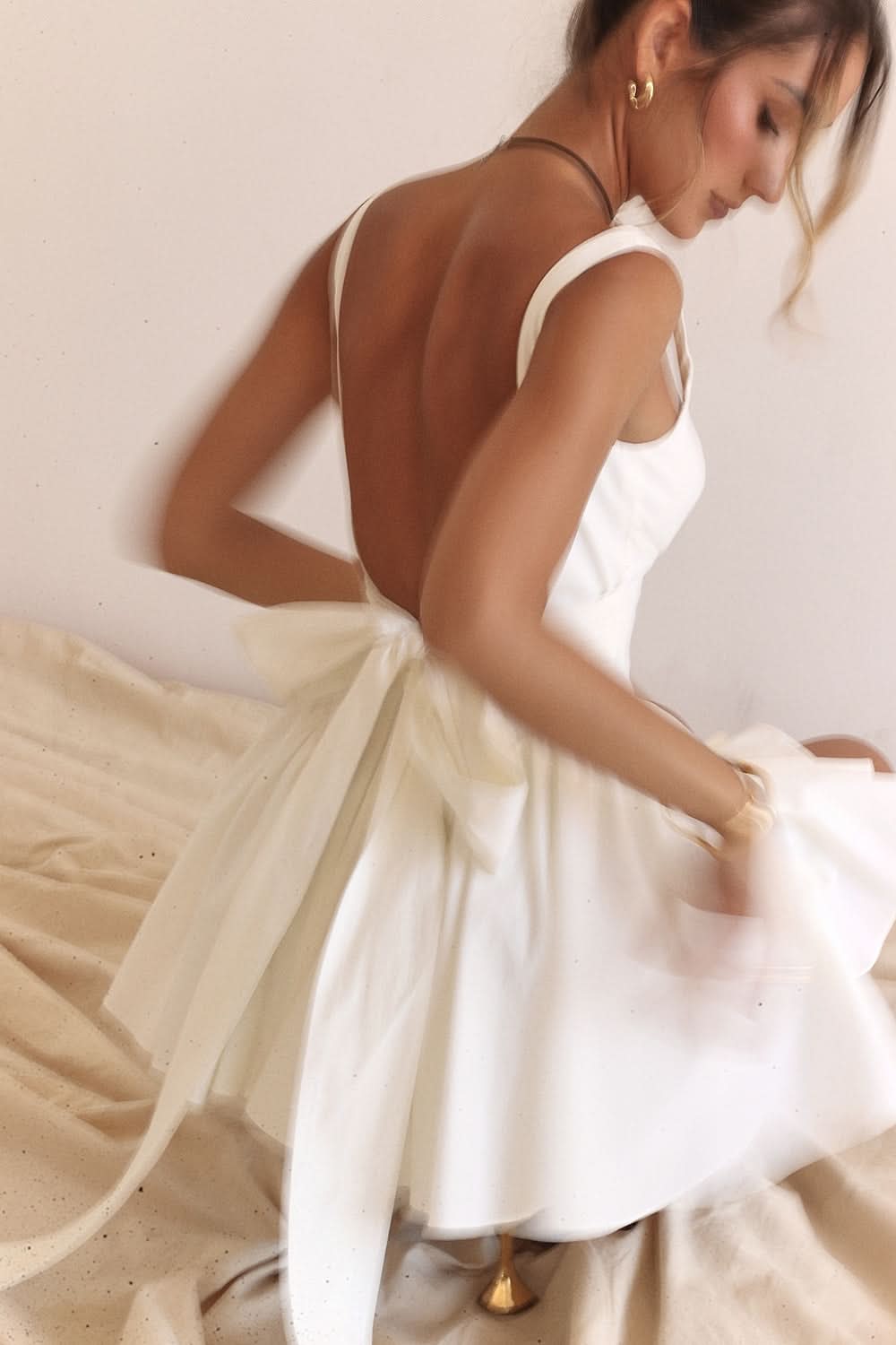 Close-up of white bow mini dress showing open back and pleated skirt
