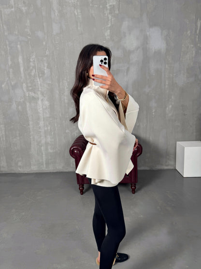 Cream poncho jacket draped view showing relaxed fit and brown belt styling