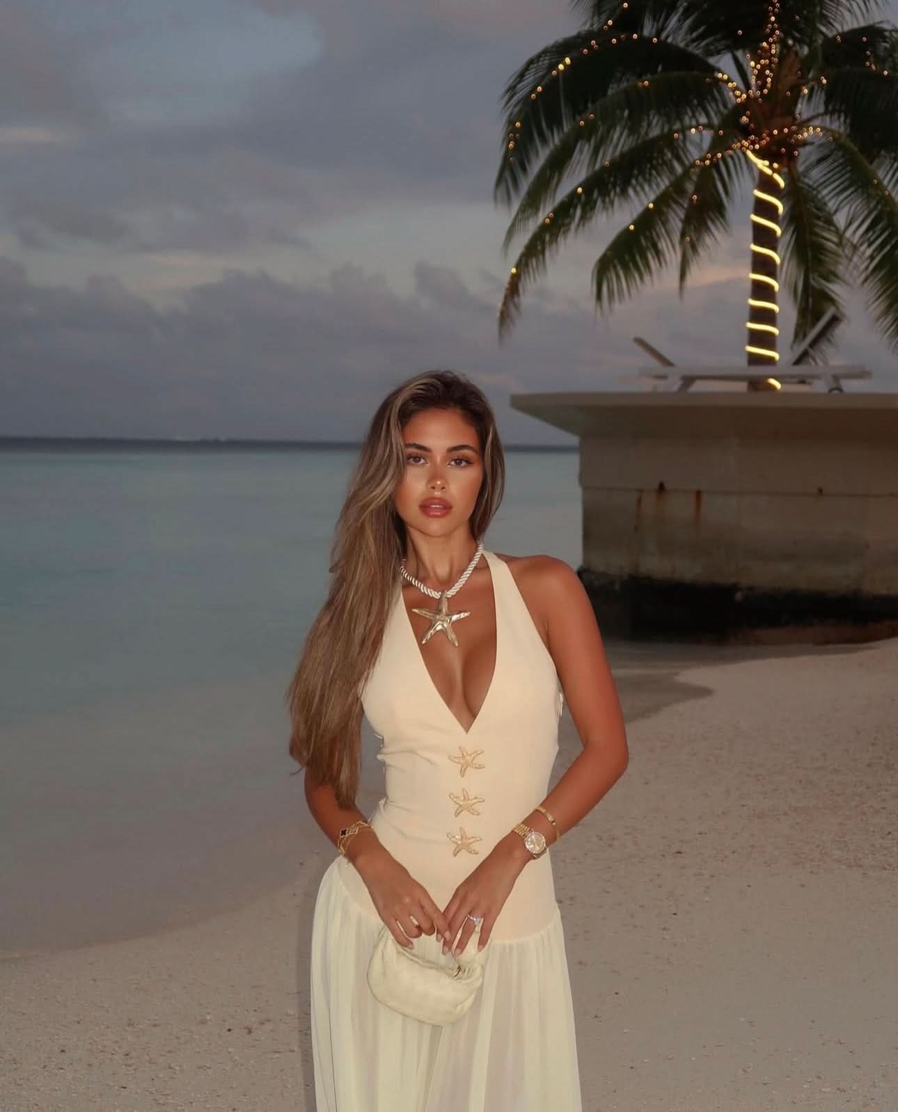 Cream halter maxi dress with gold starfish embellishments on beach at sunset