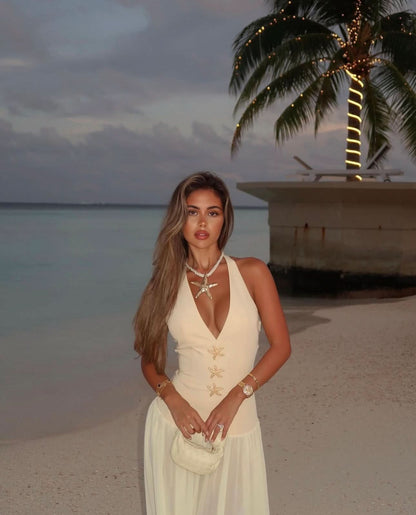 Cream halter maxi dress with gold starfish embellishments on beach at sunset