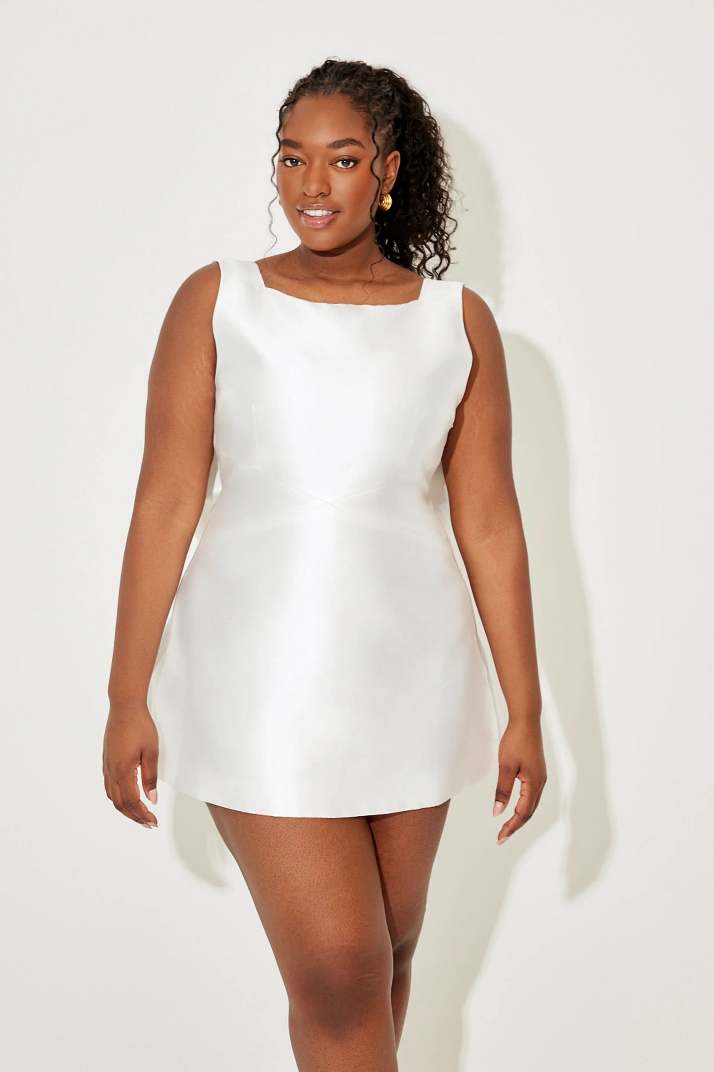 White sleeveless mini dress with round neckline and fitted silhouette
