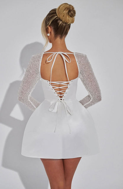 Back view of white sequin mini dress showing lace-up corset back and tie closure