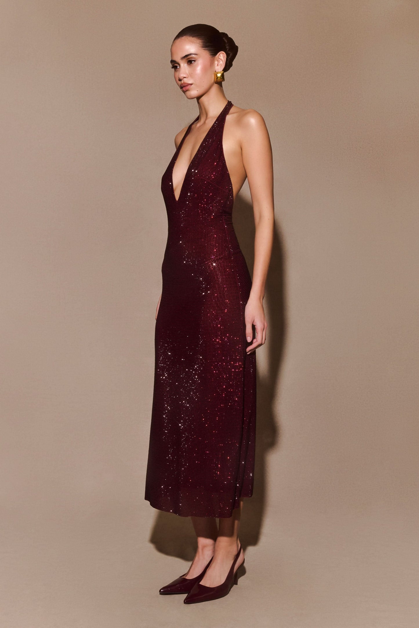Side view of burgundy sequined maxi dress with plunging halter neckline