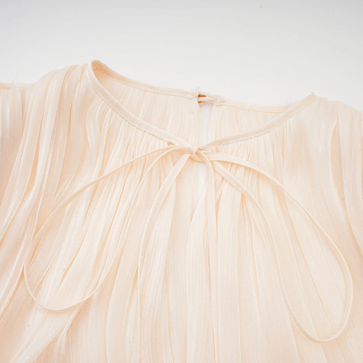 Close-up of cream pleated neckline with gathered ruffle detail