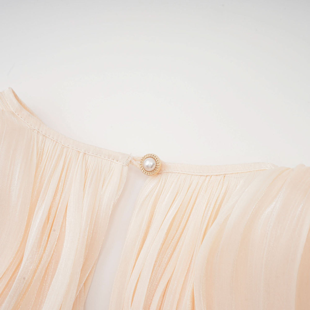 Pearl button closure detail on cream ruffled mini dress waist