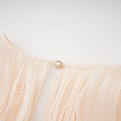 Pearl button closure detail on cream ruffled mini dress waist