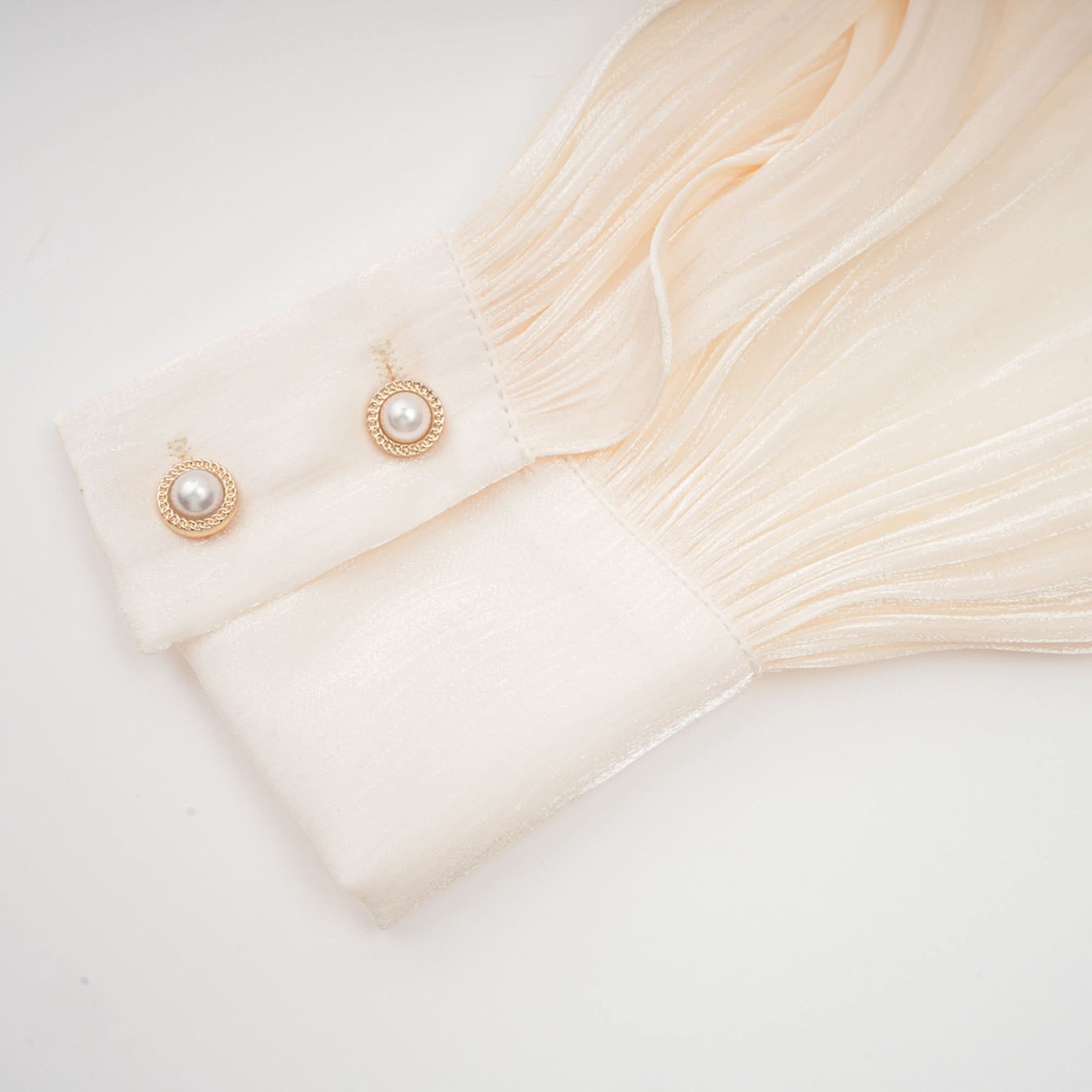 Long pleated sleeve cuff with gold pearl button embellishment