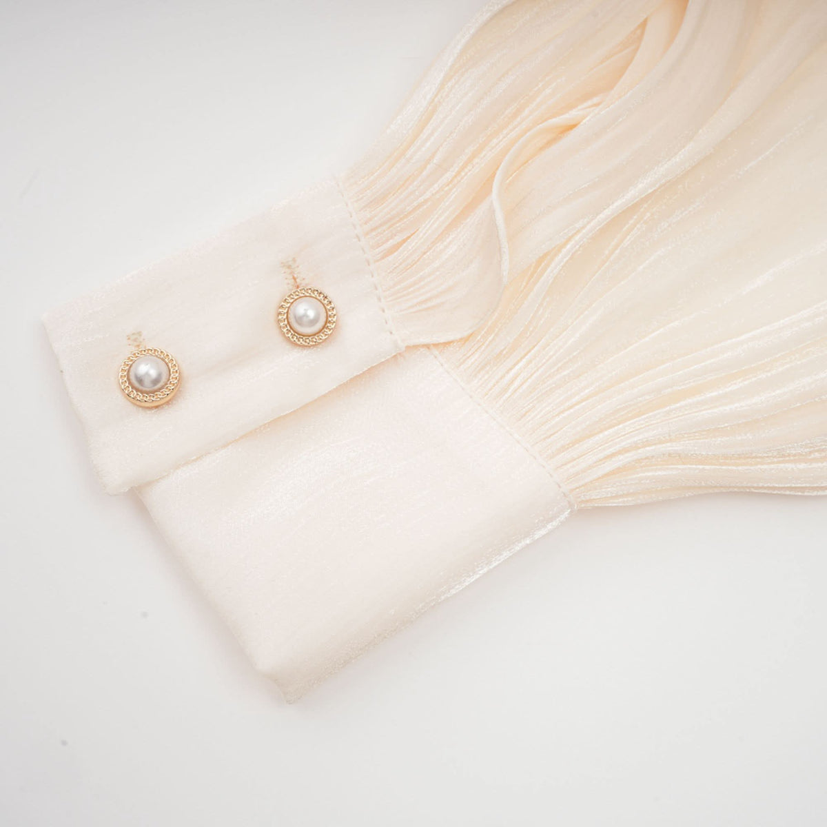 Long pleated sleeve cuff with gold pearl button embellishment