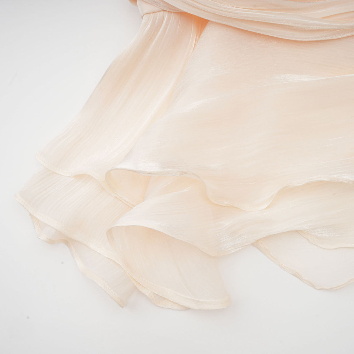 Ruffled hem of cream mini dress with layered scalloped edges