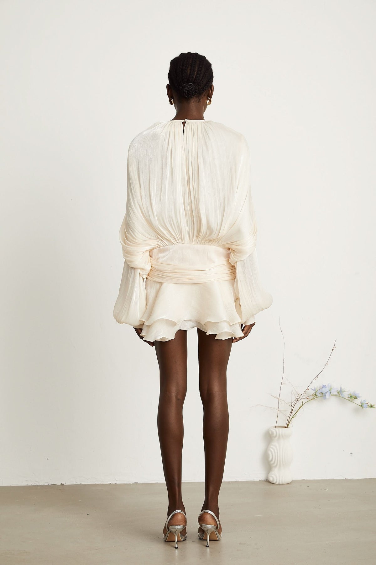 Back view of cream ruffled mini dress with voluminous pleated sleeves