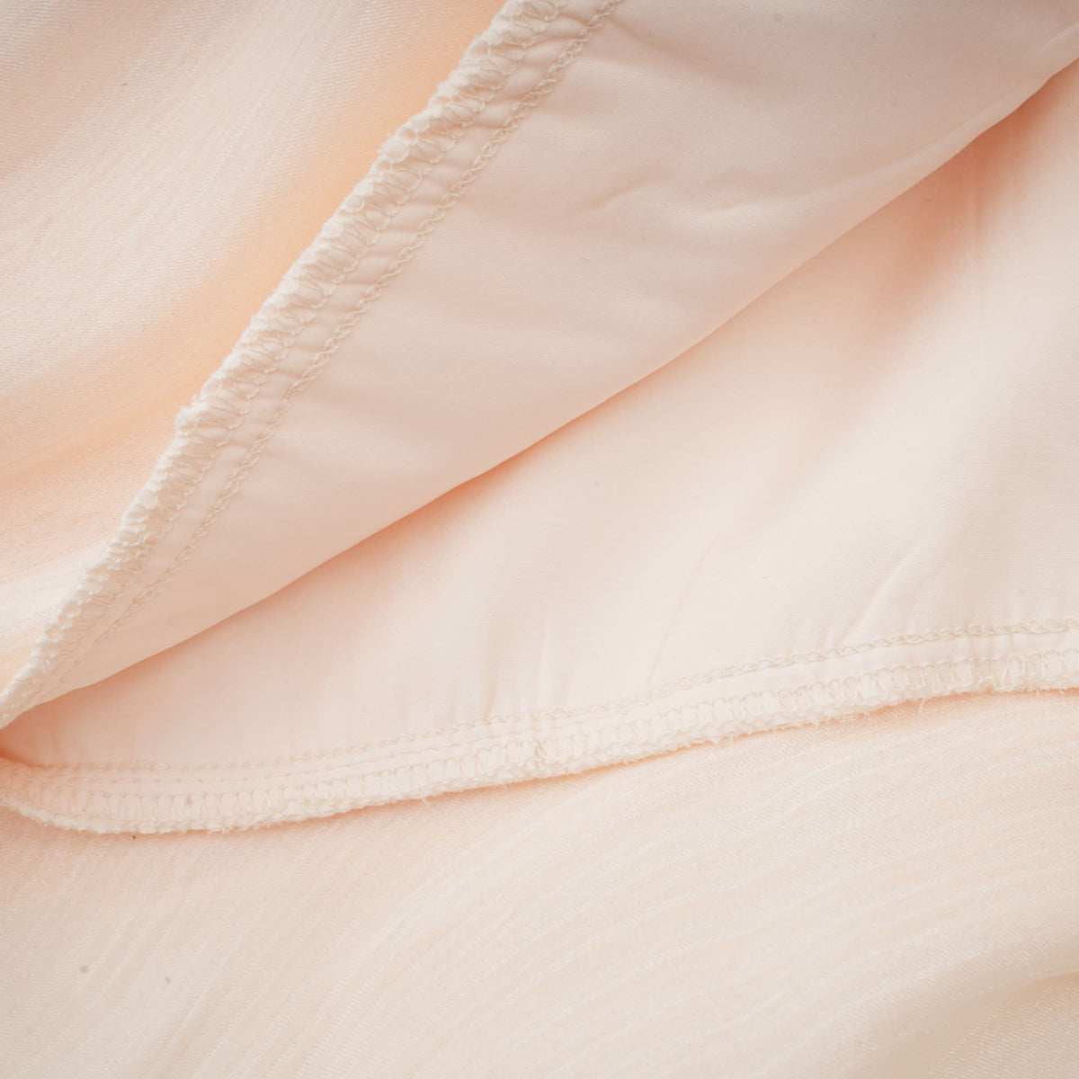 Seam detail on cream pleated dress showing fine stitching