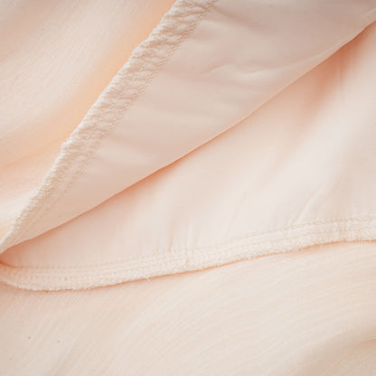 Seam detail on cream pleated dress showing fine stitching