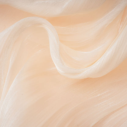 Close-up of cream mini dress ruffled edge and flowing fabric layers