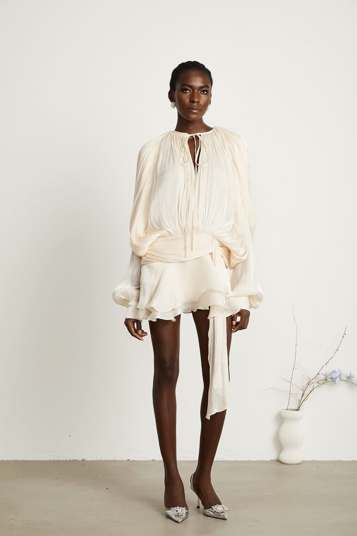Cream mini dress with gathered waist, ruffled skirt and flowing sleeves