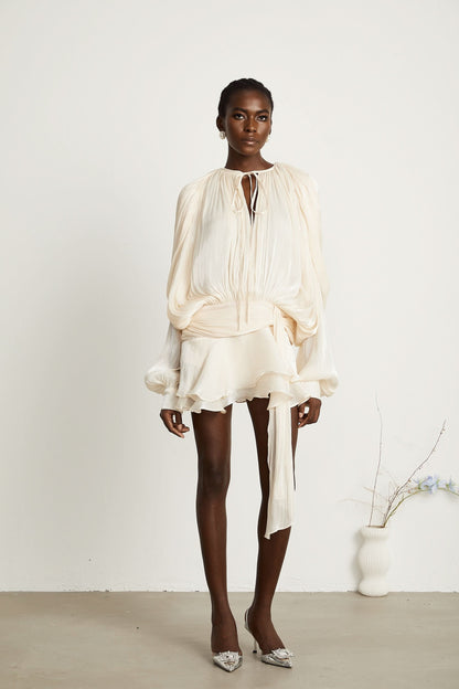 Cream mini dress with gathered waist, ruffled skirt and flowing sleeves