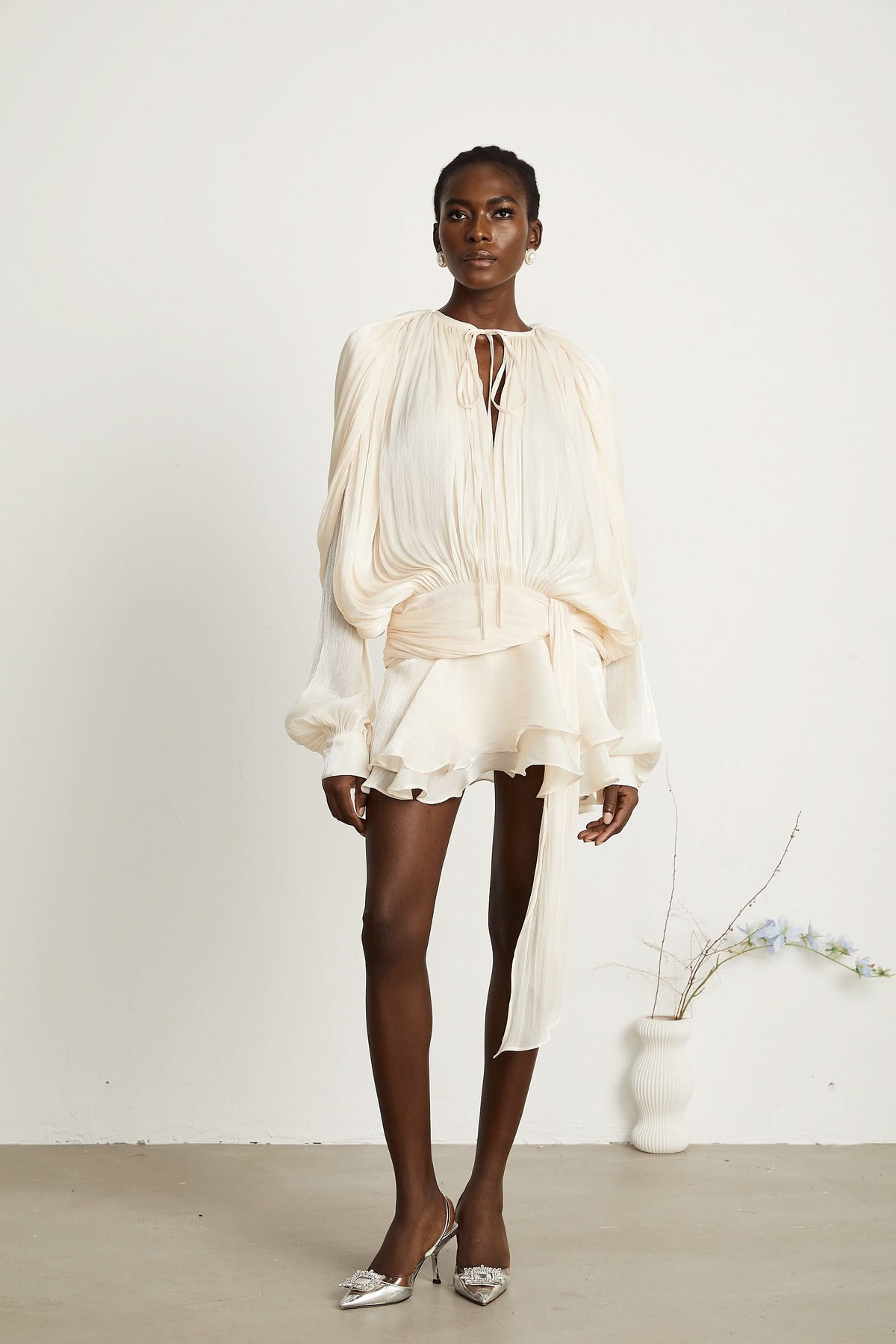 Cream pleated mini dress with ruffled skirt and draped balloon sleeves