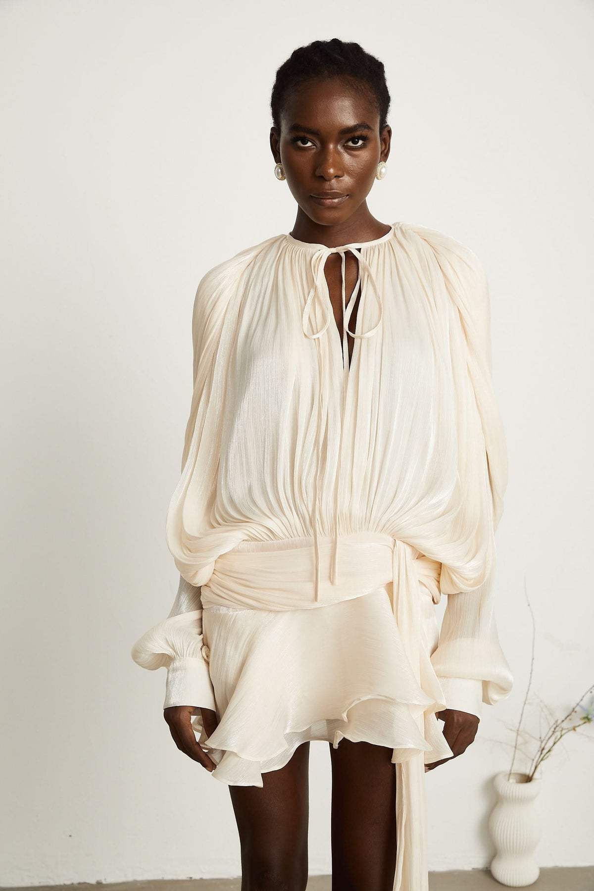 Cream mini dress detail showing ruffled hem and tie waist closure