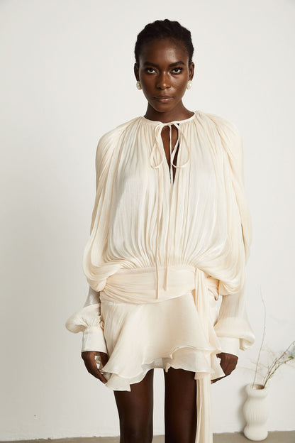 Cream mini dress detail showing ruffled hem and tie waist closure