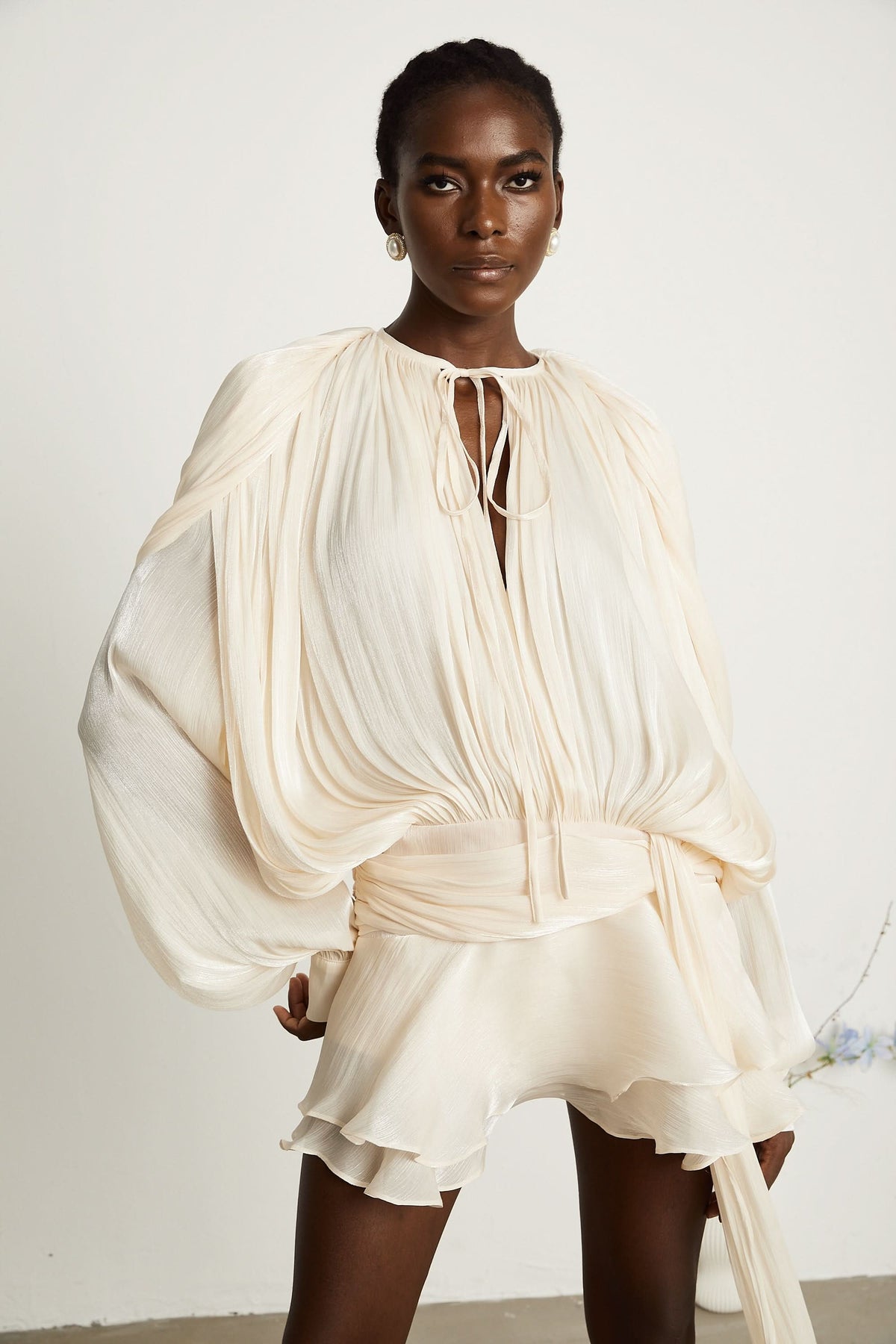 Cream pleated mini dress with gathered bodice and ruffled skirt layers