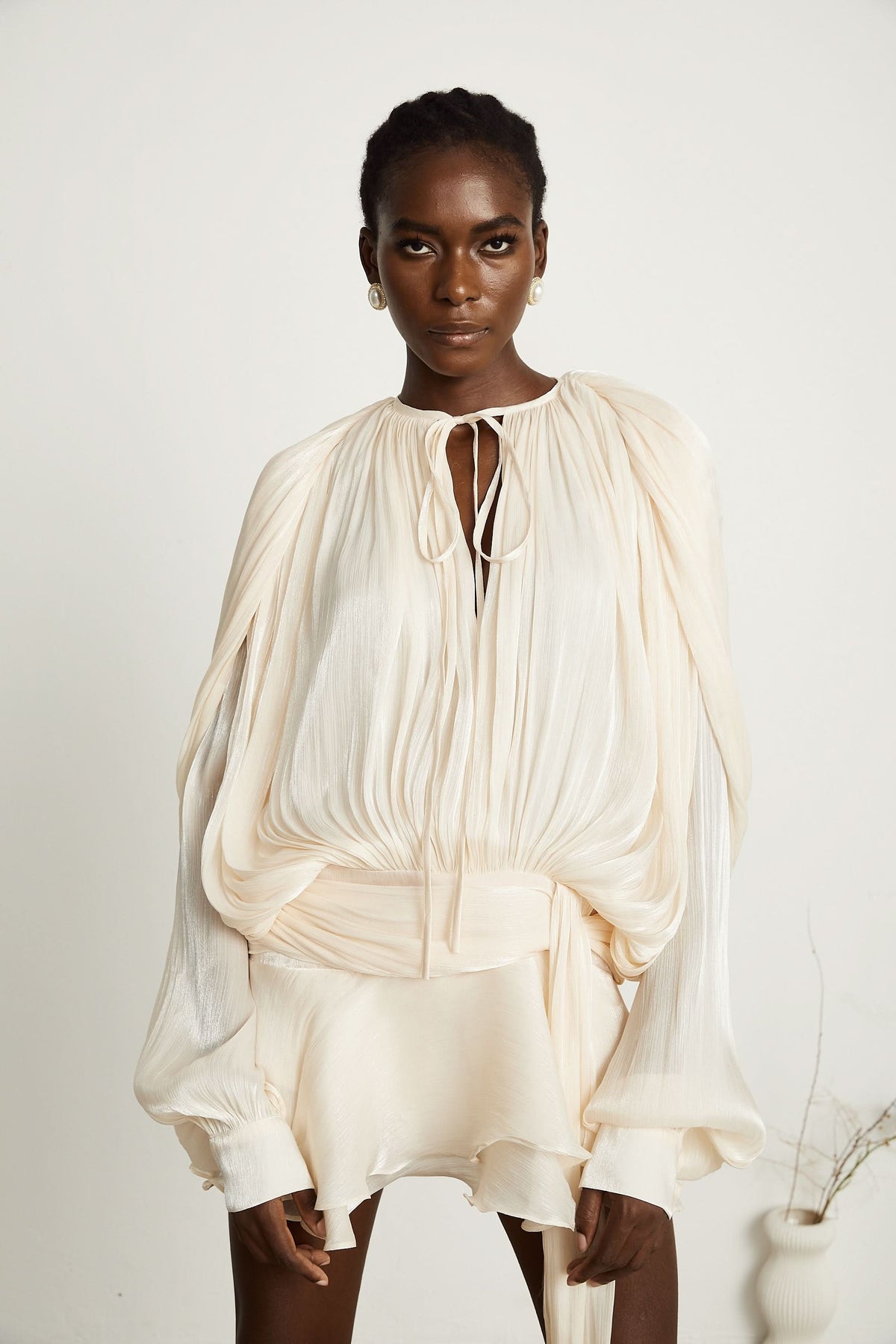 Cream pleated mini dress with ruffled hem and tie-neck keyhole cutout