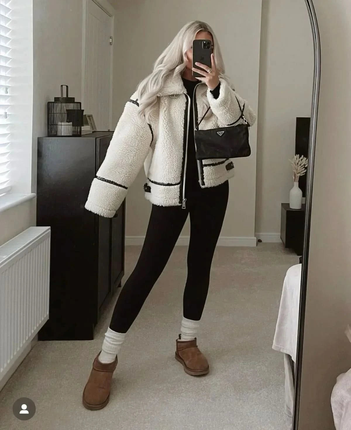 Oversized cream teddy coat with black trim styled with black pants and brown boots