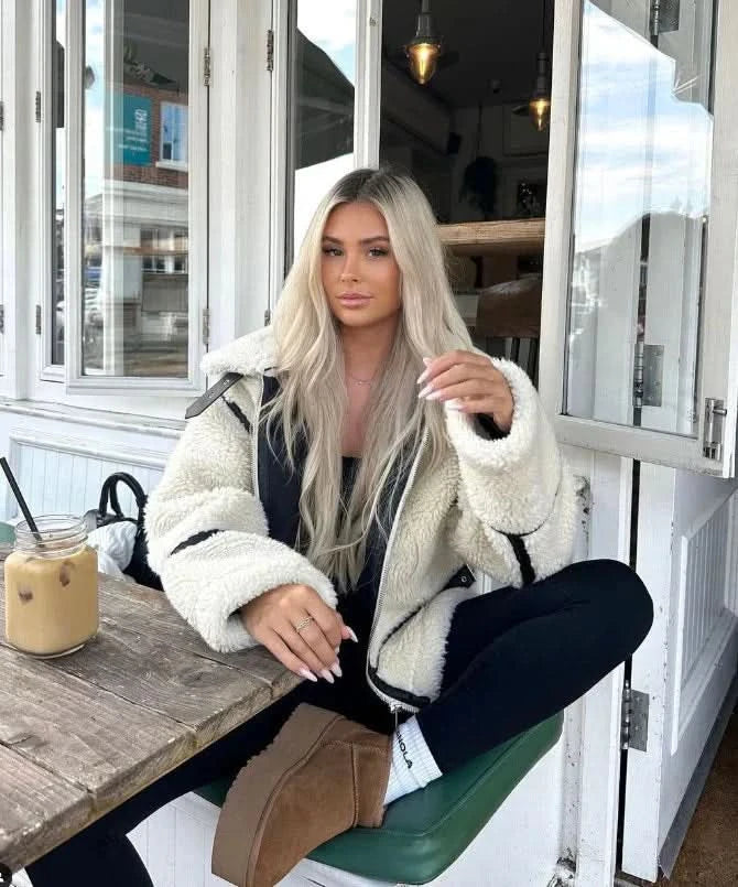 Cream fuzzy teddy coat with black piping worn casually with black pants