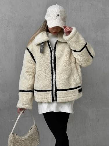 Cream teddy coat with black trim and zip front, worn with white knit and black leggings