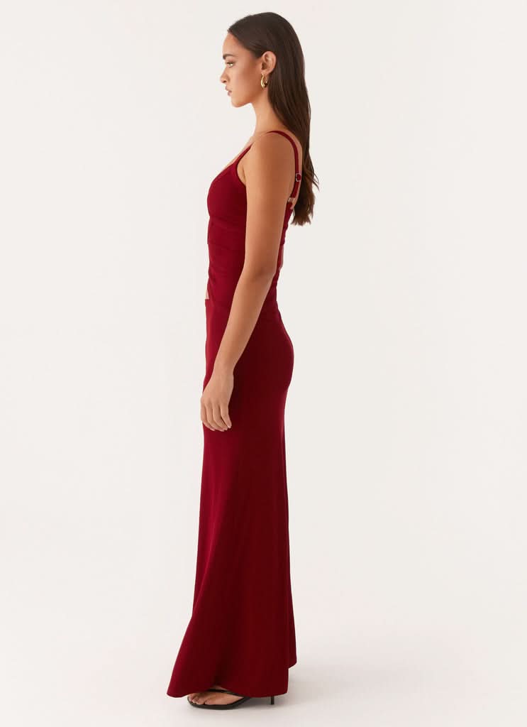 Profile view of burgundy maxi dress with fitted bodice and long skirt